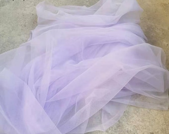 May include: A flowing, sheer fabric in a soft lavender hue. The fabric is draped and layered, creating a delicate and ethereal appearance. The word "purple" is in the top left corner.