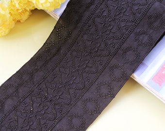 May include: Black cotton lace trim with a delicate floral pattern. The lace has a slightly raised texture and is perfect for adding a touch of elegance to any project.