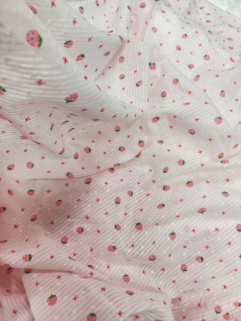 May include: Pink sheer fabric with a white stripe pattern and a small pink strawberry print.