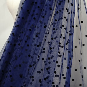 May include: Navy blue sheer fabric with black polka dots. The dots are slightly raised and have a velvet texture.