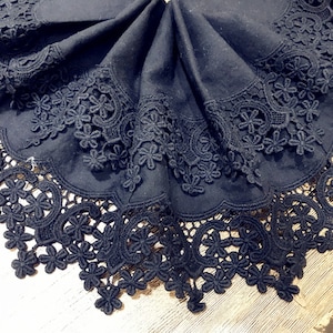 May include: Black lace trim with a scalloped edge. The lace is made of delicate floral patterns.