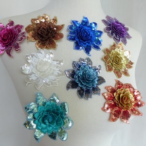 May include: Assortment of ten sequined flower appliques in various colours, including pink, brown, blue, purple, white, teal, and gold. The appliques are arranged on a white mannequin.