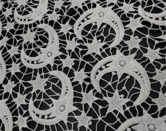 May include: White lace fabric with a repeating pattern of stars and crescent moons.