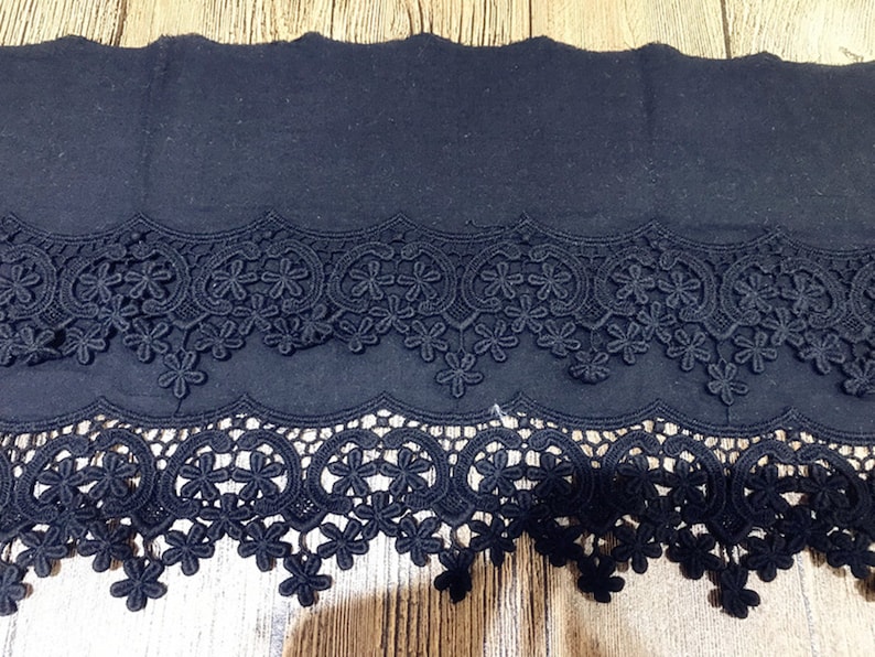 May include: Black lace trim with two rows of delicate floral designs. The trim is made of a soft, lightweight material and has a scalloped edge.