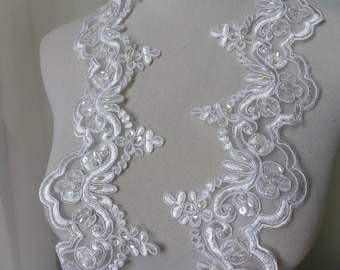 Puede incluir: Borde de encaje blanco con adornos de perlas y lentejuelas. El borde presenta un delicado diseño floral.
