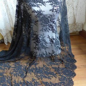 May include: Black lace fabric with a floral pattern. The lace is delicate and has a scalloped edge.