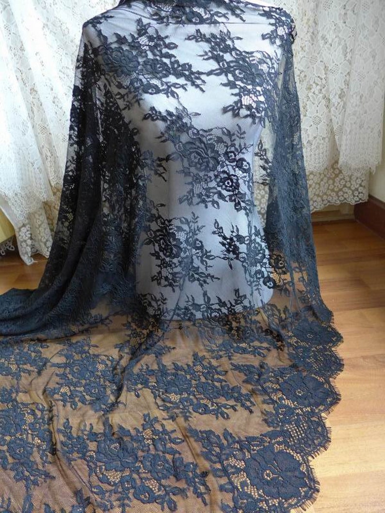 May include: Black lace fabric with a floral pattern. The lace is delicate and has a scalloped edge.