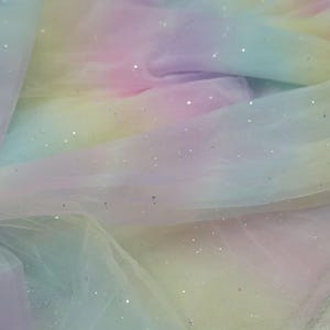 Könnte beinhalten: Regenbogen-Tüllstoff mit silbernem Glitzer. Der Stoff hat einen Farbverlauf, der oben mit Rosa beginnt und unten in Gelb übergeht.