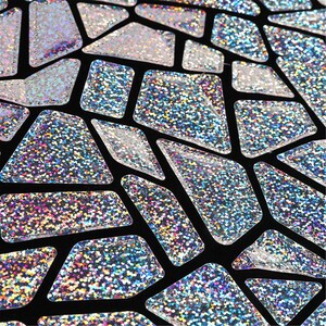 K&ouml;nnte beinhalten: Nahaufnahme eines schwarzen Stoffes mit einem geometrischen Muster aus silbernen, glitzernden Formen.