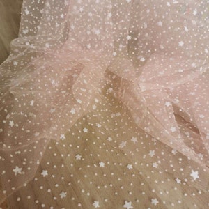 May include: Pink tulle fabric with white star and dot pattern.