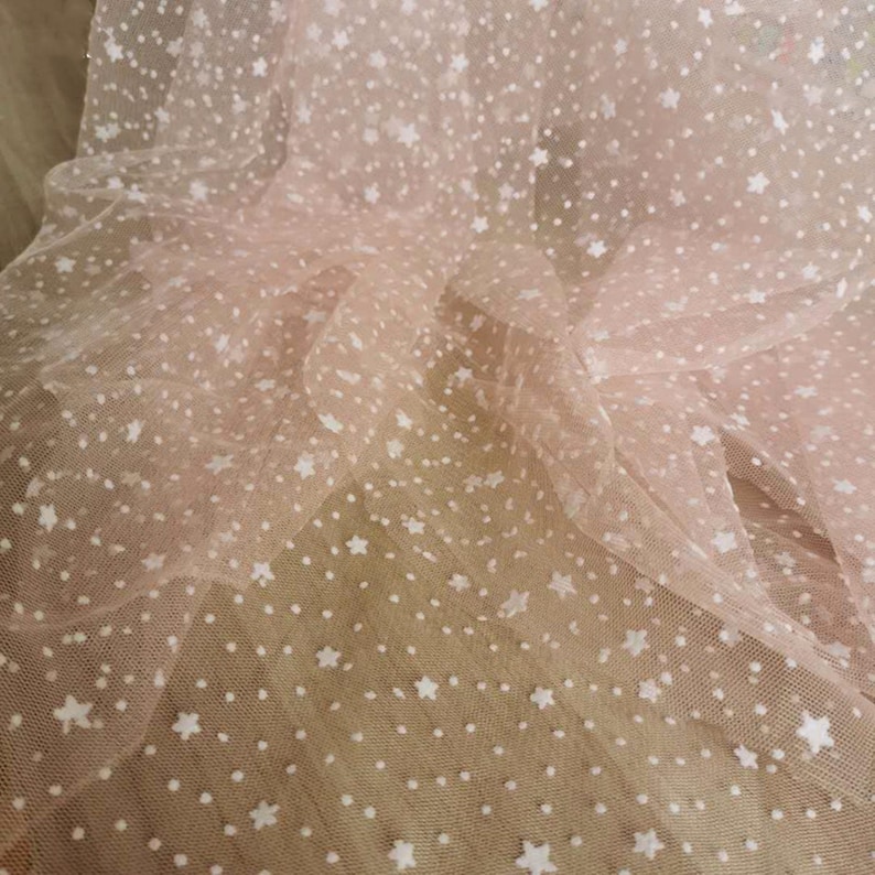 May include: Pink tulle fabric with white star and dot pattern.