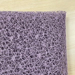 May include: A close-up of a purple, textured, mesh fabric. The fabric has a delicate, open weave pattern.