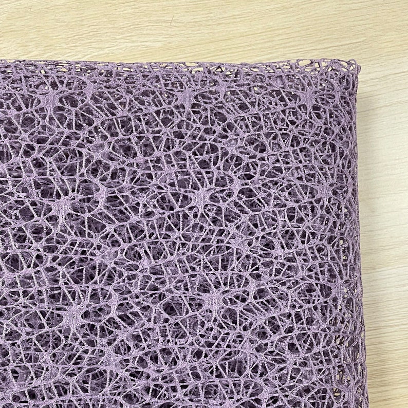 May include: A close-up of a purple, textured, mesh fabric. The fabric has a delicate, open weave pattern.