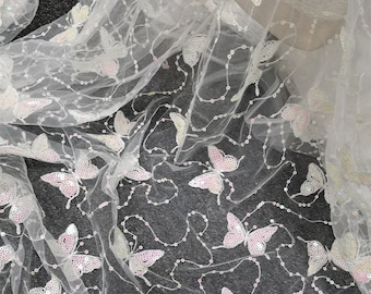 May include: White tulle fabric with iridescent butterfly sequins. The fabric is sheer and delicate, with a subtle shimmer.