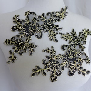 Peut inclure: Deux appliques en dentelle noire avec des broderies dorées, présentant des motifs floraux. Les appliques sont présentées sur un mannequin blanc.