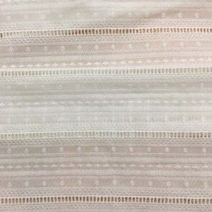 May include: White cotton fabric with a delicate embroidered pattern of geometric shapes and lines. The fabric has a subtle sheen and a soft texture.