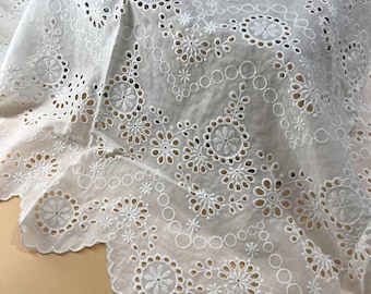 May include: White cotton fabric with a delicate eyelet lace pattern. The fabric features a scalloped edge and a repeating design of small flowers and circles.