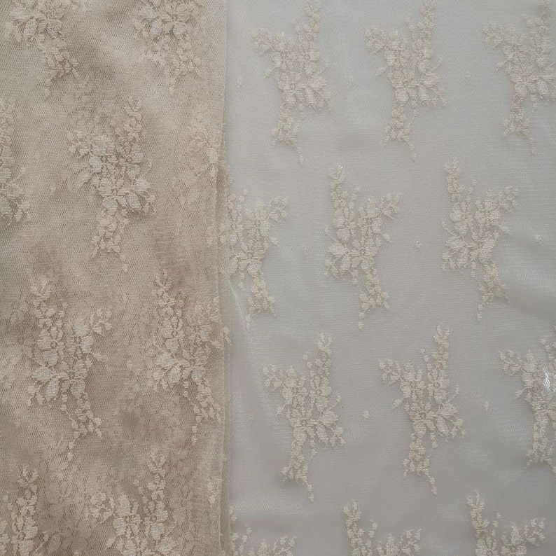 May include: Two pieces of beige lace fabric with a floral pattern. The fabric on the left is a darker shade of beige and has a more intricate pattern. The fabric on the right is a lighter shade of beige and has a simpler pattern.