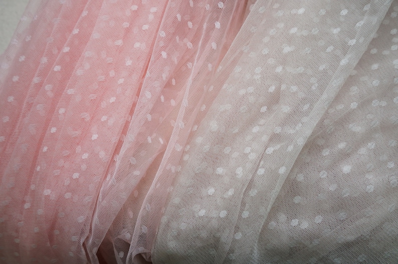Puede incluir: Dos piezas de tela transparente con lunares blancos. Una pieza es rosa y la otra es de un tono rosa m&aacute;s claro.