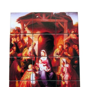 May include: A multi-tile artwork showing the Nativity scene. The image features Mary holding baby Jesus, surrounded by figures in robes, with a stable in the background. The color palette includes reds, purples, and golds. The artwork is composed of multiple square tiles.