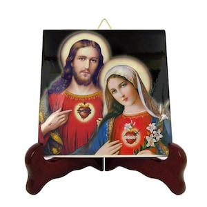 May include: Ceramic tile with a religious image of Jesus and Mary with their hearts exposed. The tile is on a wooden stand.
