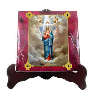 May include: A ceramic tile featuring a religious image of the Virgin Mary in a blue robe, surrounded by clouds and angels. The tile is framed with a gold border and has a red marble background.