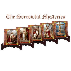 May include: Set of five framed religious art prints depicting scenes from the Sorrowful Mysteries of the Rosary. Each print features a different scene from the life of Jesus Christ, including his agony in the garden, the scourging at the pillar, the crowning with thorns, the carrying of the cross, and the crucifixion.