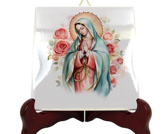 May include: A white ceramic tile with a colorful image of the Virgin Mary in a blue robe with a red sash, surrounded by pink roses. The tile is on a wooden stand.