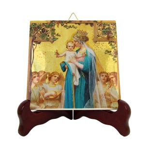 May include: A ceramic tile with a gold background and a painting of the Virgin Mary holding baby Jesus. Two angels are on either side of Mary, playing musical instruments. The tile is on a wooden stand.