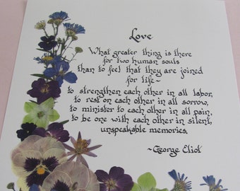 May include: A white card with a handwritten quote about love by George Eliot. The quote is surrounded by pressed flowers in shades of blue, purple, green, and white.