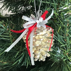 Vintage silver-plated real pinecones. Christmas ornament with silver and red ribbons, silk flower trim. No two are the same. Tarnished/aged.