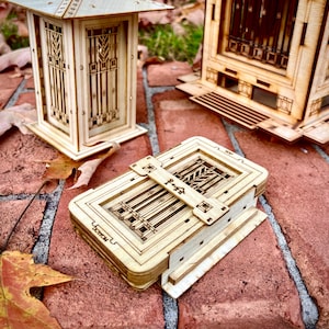 May include: A wooden model of a Japanese temple with intricate details and a small wooden box with a decorative design. The box has the text "Tomou" written on it.