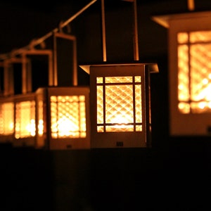 May include: A row of hanging, wooden lanterns with a lattice design and warm, glowing lights inside.