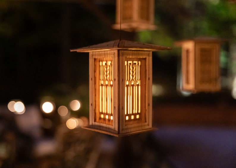 May include: A wooden lantern with a geometric design hangs from the ceiling. The lantern is lit from within, casting a warm glow.