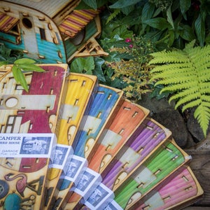 May include: A set of eight colorful wooden birdhouses shaped like vintage campers. Each birdhouse has a different color scheme and features a cutout design. The birdhouses are labeled "Vintage Camper Bird House" and "One Man, One Garage, One Play, One Love".