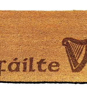 May include: A brown coir doormat with the word "fàilte" and a stylised harp design.