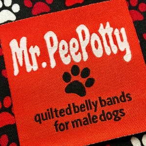 May include: Red fabric label with white text that reads "Mr. Pee Potty" and black text that reads "quilted belly bands for male dogs". A black paw print is centered above the text.