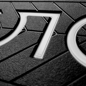 May include: A close-up of a black and white sign with the letters "O" and "P" in white. The letters are raised and have a textured surface.