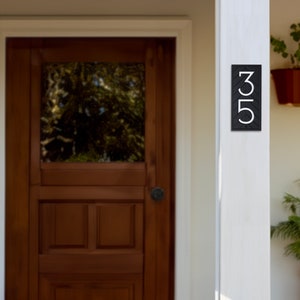 May include: Black house number sign with white numbers 35 on a white wooden post.