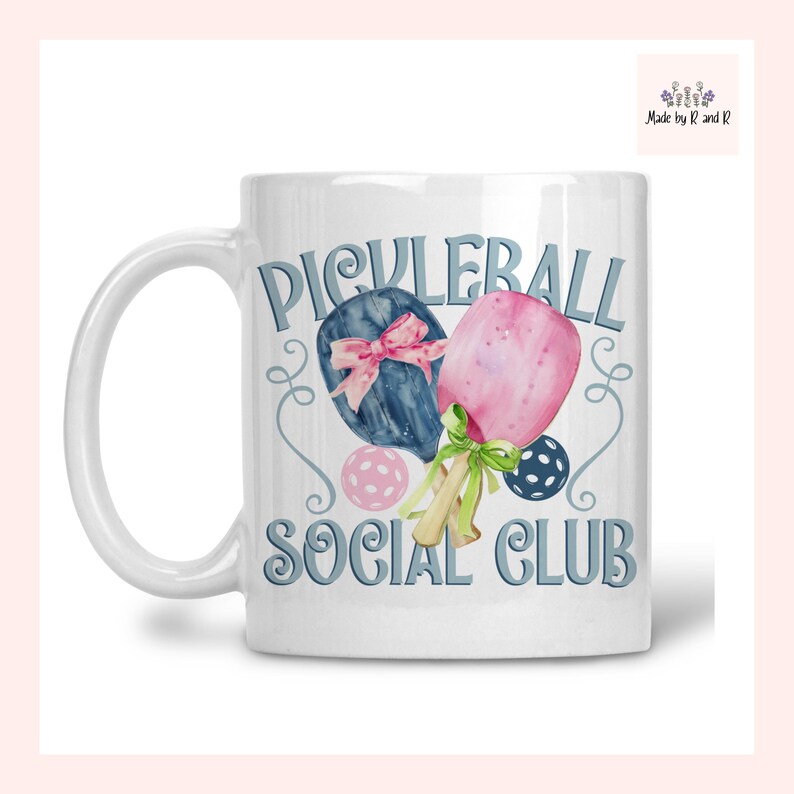 May include: White ceramic mug with the words "PICKLEBALL SOCIAL CLUB" in light blue script. The mug features watercolour illustrations of pickleball paddles, balls, and bows in shades of pink, blue, and green.
