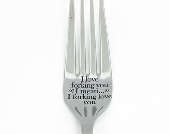 May include: A stainless steel fork with four prongs. The handle is engraved with the words "I love forking you, I mean... I forking love you" in black text. The fork is set against a white background.