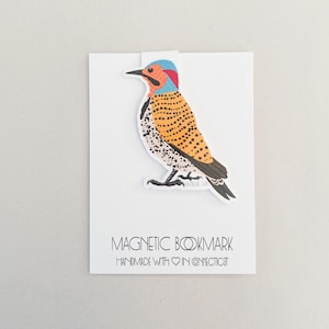 May include: A magnetic bookmark featuring a colorful illustration of a bird with a yellow, orange, and black spotted pattern. The text "MAGNETIC BOOKMARK HANDMADE WITH ♥ IN CONNECTICUT" is printed below the bird.