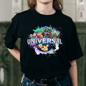 May include: Black t-shirt featuring the word "UNIVERSAL" in silver lettering, surrounded by a colorful splash design. The design includes various cartoon characters such as the Minions, Spider-Man, and the Simpsons.