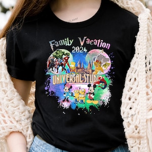 Könnte beinhalten: Schwarzes T-Shirt mit einer farbenfrohen Grafik mit Figuren von Marvel, den Simpsons und Disney, mit dem Text "Family Vacation 2024 Universal Studios". Das Design umfasst Hulk, Captain America, Bart Simpson, Mickey und Minnie Mouse.