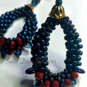 May include: A pair of handmade earrings with a teardrop shape. The earrings are made with dark blue and iridescent beads, and red beads are interspersed throughout. The earrings are attached to gold-colored ear wires.
