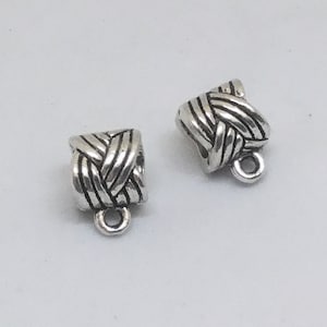 May include: Two silver metal cord end caps with a braided design. The caps have a small loop at the bottom.