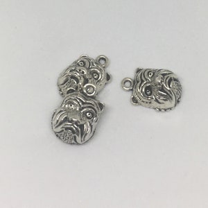 May include: Three silver bulldog head charms with loop attachments. The charms are detailed with realistic features, including the dog's nose, eyes, and wrinkles.