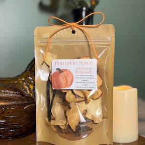 May include: A brown kraft paper pouch containing dried pumpkin spice stovetop potpourri, tied with an orange string bow. The white label features a pumpkin illustration and the text: Pumpkin Spice Stovetop Potpourri, with instructions.