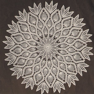 Puede incluir: Un encaje de ganchillo blanco con un diseño circular que presenta un patrón repetitivo de pequeñas hojas puntiagudas. El encaje tiene un diseño delicado e intrincado.