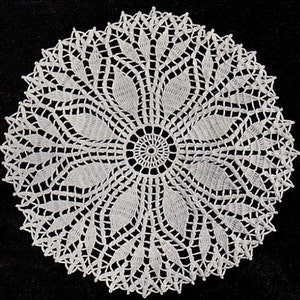 May include: White crocheted doily with a delicate floral design. The doily has a circular shape and is made with intricate stitches.